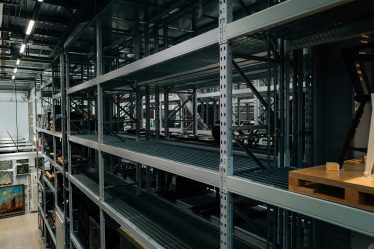 Wysokie stalowe regały magazynowe z półkami do przechowywania towarów w dużym magazynie przemysłowym.