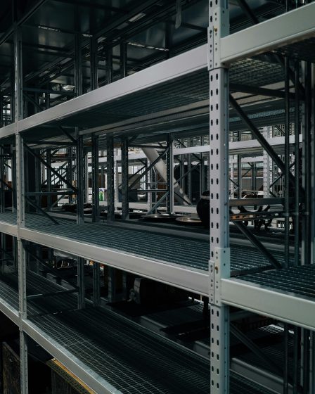 Wysokie stalowe regały magazynowe z półkami do przechowywania towarów w dużym magazynie przemysłowym.