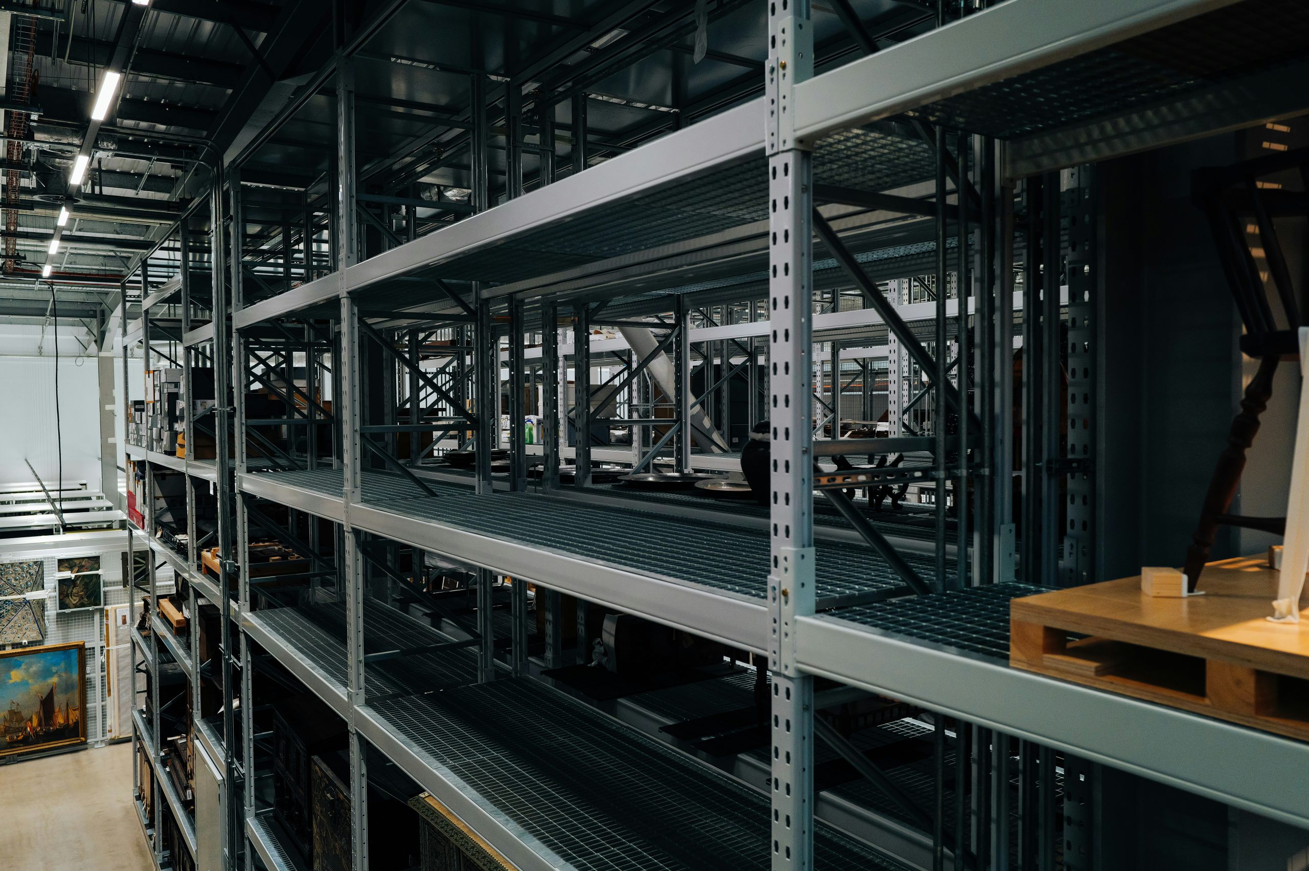 Wysokie stalowe regały magazynowe z półkami do przechowywania towarów w dużym magazynie przemysłowym.