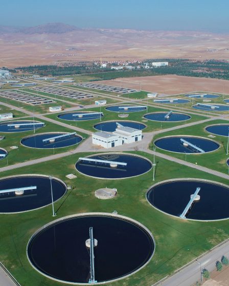 Rozległy kompleks oczyszczalni ścieków z wieloma okrągłymi basenami osadowymi i infrastrukturą technologiczną na tle otwartego terenu.
