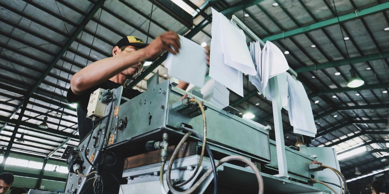 Pracownik obsługujący maszynę produkcyjną w zakładzie celulozowo-papierniczym. Ochrona infrastruktury przed wilgocią i chemią.