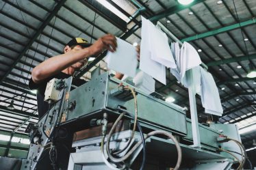 Pracownik obsługujący maszynę produkcyjną w zakładzie celulozowo-papierniczym. Ochrona infrastruktury przed wilgocią i chemią.
