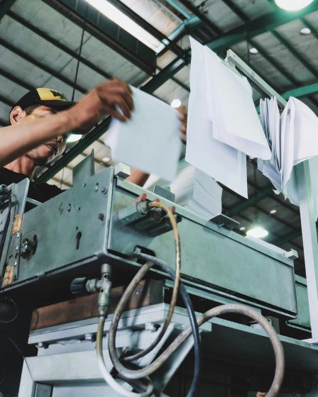Pracownik obsługujący maszynę produkcyjną w zakładzie celulozowo-papierniczym. Ochrona infrastruktury przed wilgocią i chemią.