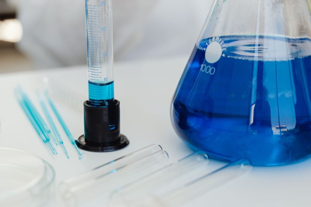 sprzęt laboratoryjny, w tym probówki i kolby Erlenmeyera z niebieską cieczą